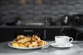 a cup of tea with a plate of croissants on the kitchen table. dessert side view. morning coffee with sweets. recipe of dish