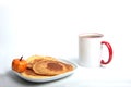 Cup of tea and a plate of pumpkin pancakes isolated on white background