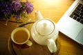 Cup, tea pot ,cookies and laptop on wooden desk Royalty Free Stock Photo