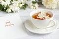 Cup of tea, pouring honey from a spoon in a jar, Jasmine flowers on a light wooden background. Copy space. Royalty Free Stock Photo