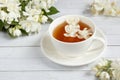 Cup of tea, pouring honey from a spoon in a jar, Jasmine flowers on a light wooden background. Copy space Royalty Free Stock Photo