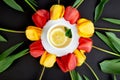 Cup of tea with red and yellow tulip around. Royalty Free Stock Photo