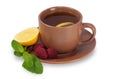 Cup of tea on a saucer with lemon, raspberry and mint leaves iso Royalty Free Stock Photo