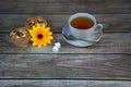 A cup of tea on a saucer with a spoon and two cupcakes on a napkin with a yellow flower, next to two cubes of sugar Royalty Free Stock Photo