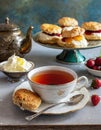 A cup of tea and scones with jam and cream.