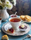 A cup of tea and scones with jam and cream.