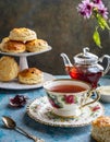 A cup of tea and scones with jam and cream.