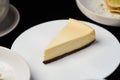 Cup of tea and slice of cheesecake on white plate on table Royalty Free Stock Photo