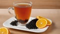 A cup of tea with a slice of orange and a spoonful of black tea leaves