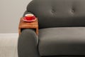 Cup of tea on sofa with wooden armrest table in room. Interior element Royalty Free Stock Photo