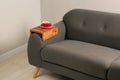 Cup of tea on sofa with wooden armrest table in room. Interior element Royalty Free Stock Photo