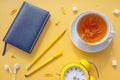 Cup of tea with splashes, lumps of sugar, notebook in blue cover, pen and pencil,