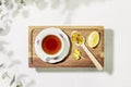 Cup of tea with spoon, slice of lemon and dry flowers on wooden small tray