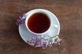 A Cup of tea and a sprig of lilac on a wooden background