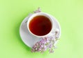 A Cup of tea and a sprig of lilac on a wooden background