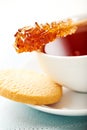 Cup of tea with sugar swizzle stick and biscuit