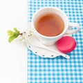 Cup of tea and sweet and colourful french macaroon and a cherry