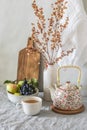 A cup of tea, a teapot, a bowl of fruit on a bright table with dried flowers in a vase. Autumn mood home still life Royalty Free Stock Photo