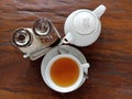 Cup of tea and teapot with brown and white sugar on brown wooden table background. Royalty Free Stock Photo