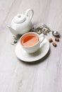 Cup of Tea and teapot, spoon, sugar, on a light wooden