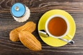 Cup with tea, teaspoon, sugar and two eclairs on table