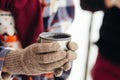 A cup of tea from a thermos on winter picnic in the woods. Woman hand`s in a warm gloves