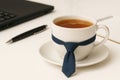 A cup of tea with a tie in the office. Royalty Free Stock Photo