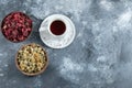 Cup of tea and two bowls of dried flowers on marble background