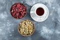 Cup of tea and two bowls of dried flowers on marble background