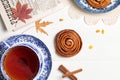 A cup of tea in a vintage cup, cinnamon and raisin buns and a newspaper on a light wooden background. Top view.