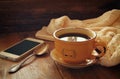 Cup of tea with warm sweater and smartphone on wooden table Royalty Free Stock Photo