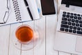 Cup of tea on white desktop with laptop, notebook, smartphone, pen and glasses. Business concept Royalty Free Stock Photo