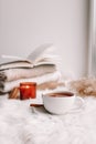 A cup of tea on the window with burning candles and sweaters Royalty Free Stock Photo