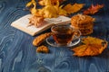 Cup of tea wit old book and autumn leaves on wooden table