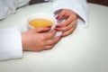 Cup of tea in womans hands. Girl in white coat at table Royalty Free Stock Photo