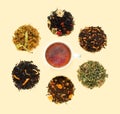 Cup of tea on yellow table with large assortment of herbal, flower, berry and leaf dry teas