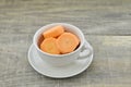 Cup with thick slices carrots on wooden background