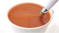 A cup of tomato soup being stirred