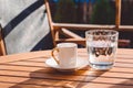 A cup of Turkish coffee and a glass of water on the wooden table on a terrace in a garden, coffee break