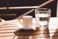 A cup of Turkish coffee and a glass of water on the wooden table on a terrace in a garden, coffee break