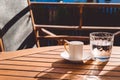 A cup of Turkish coffee and a glass of water on the wooden table on a terrace in a garden, coffee break