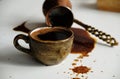 Cup of turkish coffee and overturned cezve with spilled coffee. White background, close-up