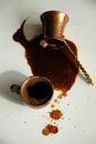 Cup of turkish coffee and overturned cezve with spilled coffee. White background, top view