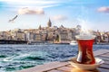 A cup of Turkish tea in a traditional glass against the background of the Golden Horn and the Galata Tower in Istanbul Royalty Free Stock Photo