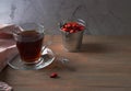 A Cup of vitamin tea with rosehip and a tin bucket of fruit on a brown wooden background . Natural herbal tea.