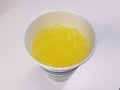 Cup on white surface with yellow liquid and ice Royalty Free Stock Photo