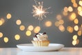 Cupcake with burning sparkler on table against blurred festive lights Royalty Free Stock Photo