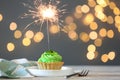 Cupcake with burning sparkler on table against blurred festive lights. Space for text Royalty Free Stock Photo