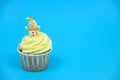 cupcake decorated with snowman figurine on a vibrant blue background copy space