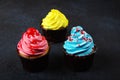 Cupcake cakes yellow, pink, blue on a dark background